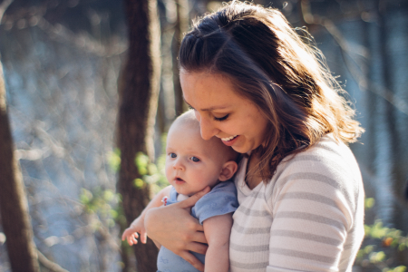 woman holding a young baby outside and smiling