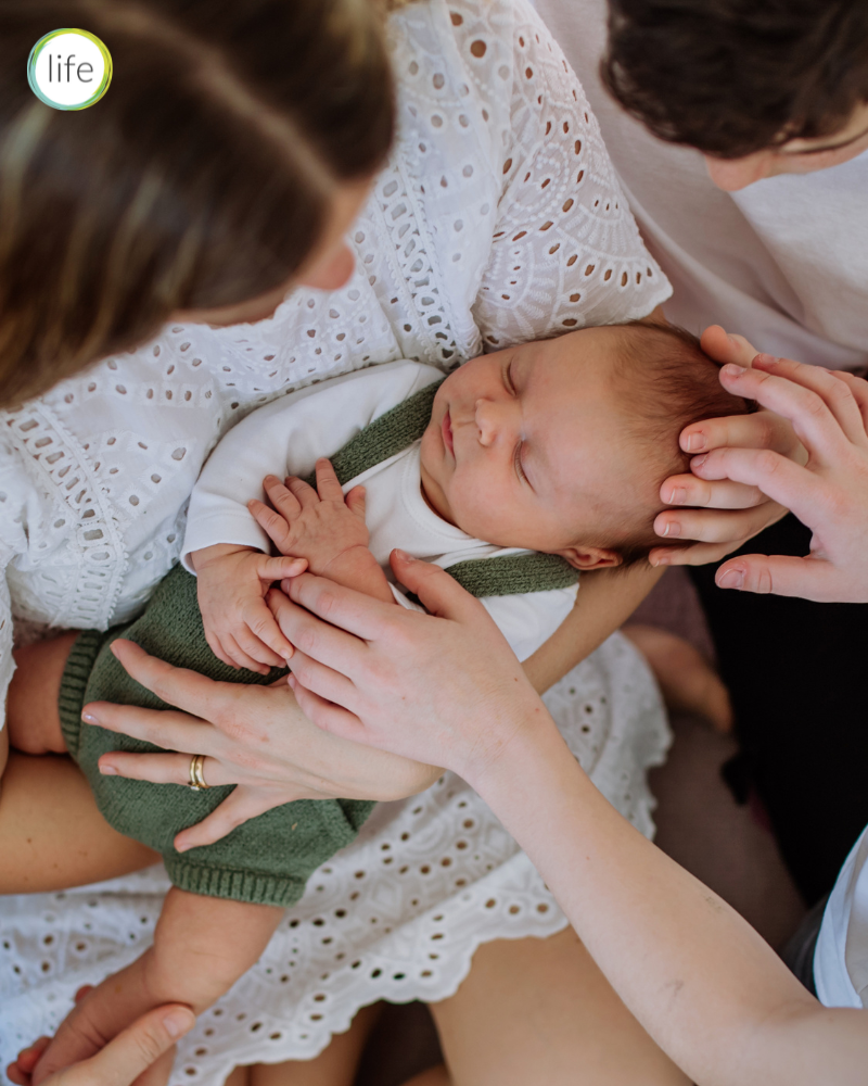view of mum from above holding newborn with other children gathered around