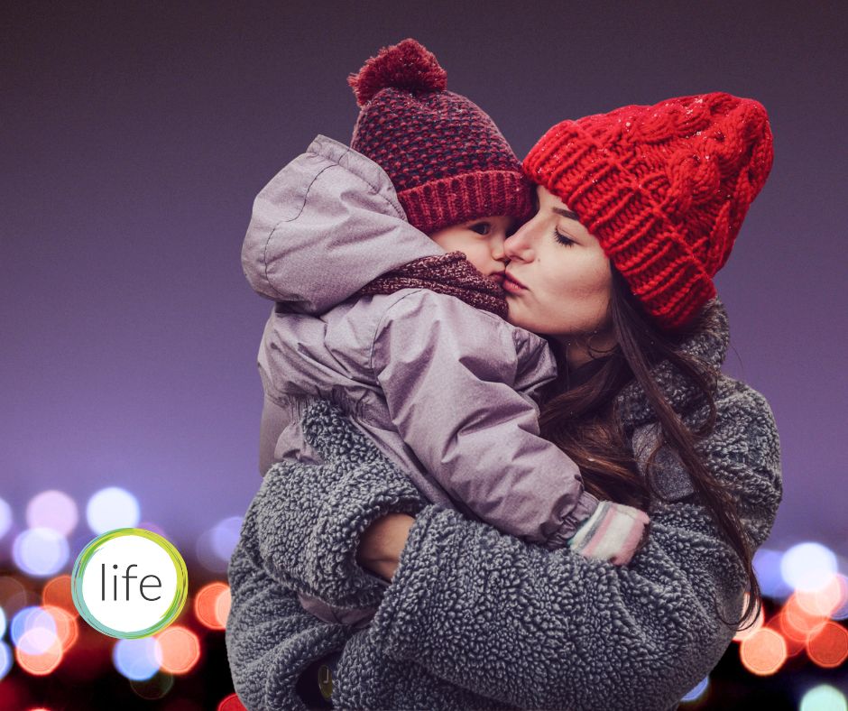 Young mum with infant wrapped up in winter coats and hats